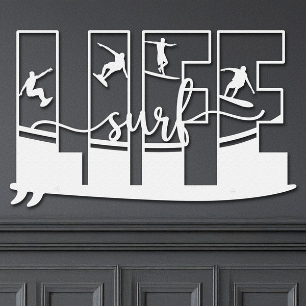 White metal wall art featuring the word 'LIFE' with each letter containing a silhouette of a surfer in different poses. The word 'surf' is written in cursive below, with a stylized wave design connecting the letters riding on a surf board hanging on a dark grey wall.