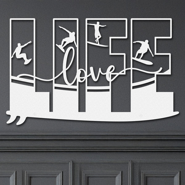 White decorative metal wall art featuring the word 'LIFE' with silhouettes of surfers in various poses within each letter, and the word 'love' written in cursive script in the center.