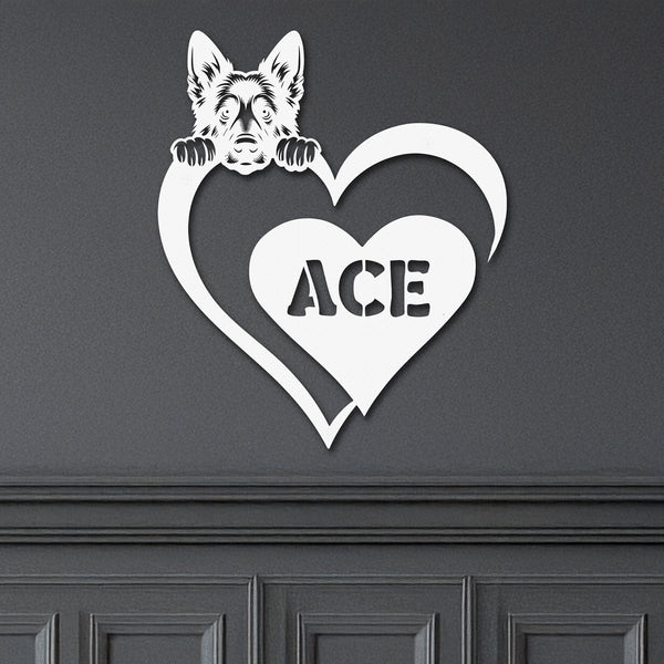 White metal sign with a German Shepard dog silhouette peeking over a heart, with the name "Ace" written inside the heart, mounted on a gray wall.