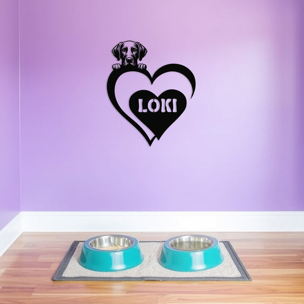 Personalized metal sign featuring a Labrador and a heart-shaped name plaque, displayed on a purple wall above dog bowls.