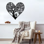 Black metal heart wall art featuring two children playing beneath a tree, displayed above an armchair with a plaid blanket.