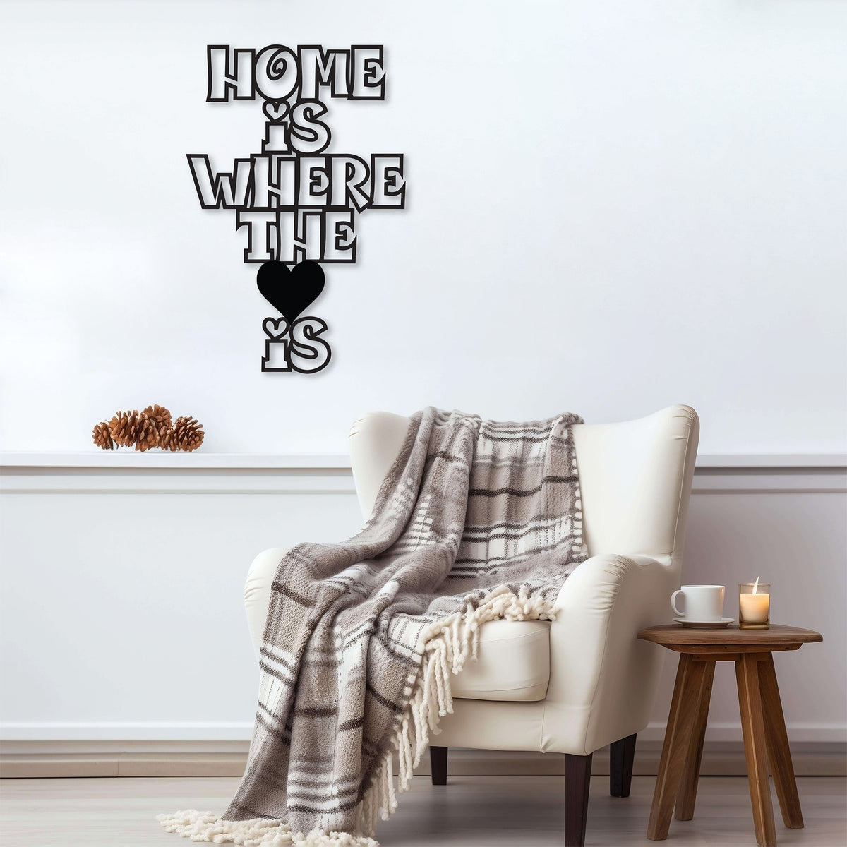 Black metal wall decor with the phrase 'Home Is Where The Heart Is' displayed above an armchair with a plaid blanket.