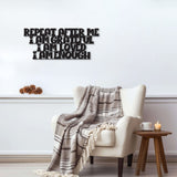 Black metal die-cut sign with the phrase 'Repeat After Me I Am Grateful I Am Loved I Am Enough' displayed above a cozy armchair with a plaid blanket.