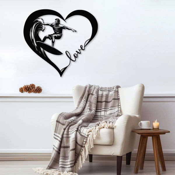 Black metal wall art featuring a surfer riding a wave inside a heart shape with the word 'love' written in cursive. The art is displayed above a cozy armchair with a plaid blanket draped over it.