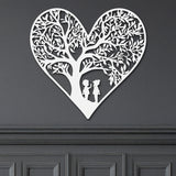 Close-up of white metal heart wall art with intricate tree and children design.