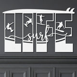 White decorative metal wall art featuring the word 'LIFE' with silhouettes of surfers in various poses within each letter, and the word 'surf' written in cursive script in the center.