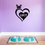 Personalized metal sign featuring a pug and a heart-shaped name plaque, displayed on a purple wall above dog bowls.