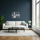 Silver metal die-cut sign with the phrase 'Live Laugh Love' in a living room setting with a white sofa and coffee table.