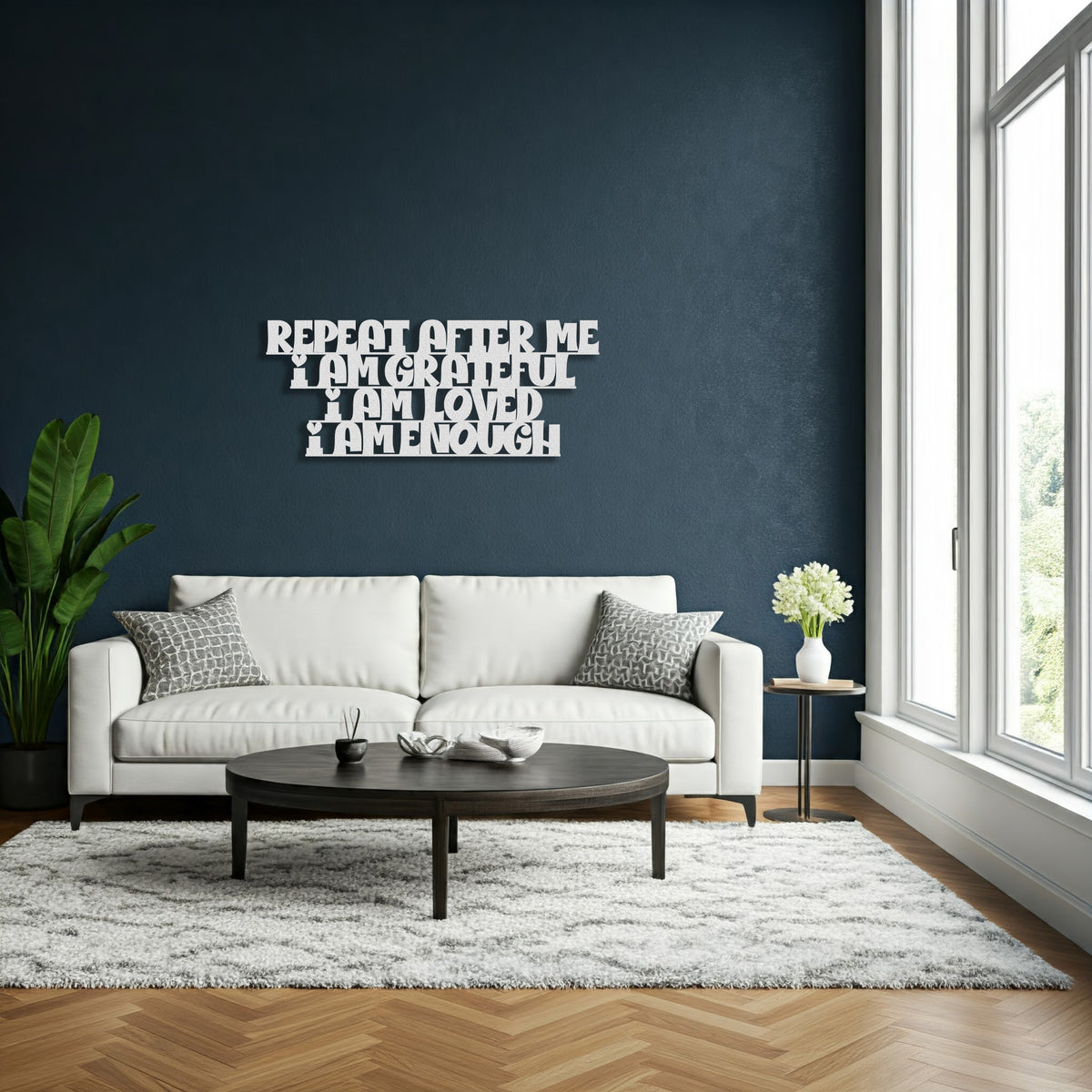 Silver metal die-cut sign with the phrase 'Repeat After Me I Am Grateful I Am Loved I Am Enough' in a living room setting with a white sofa and coffee table.