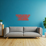 Red metal die-cut sign with the phrase 'Repeat After Me I Am Grateful I Am Loved I Am Enough' displayed above a gray sofa in a room with a blue wall