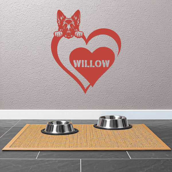 Personalized pet red metal wall sign  featuring a dog silhouette and the name "Willow" mounted on a tan wall above dog food bowls.