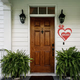 A front porch with a heart shaped red metal sign with a labrador peeking over the top, in the heart is the house number 